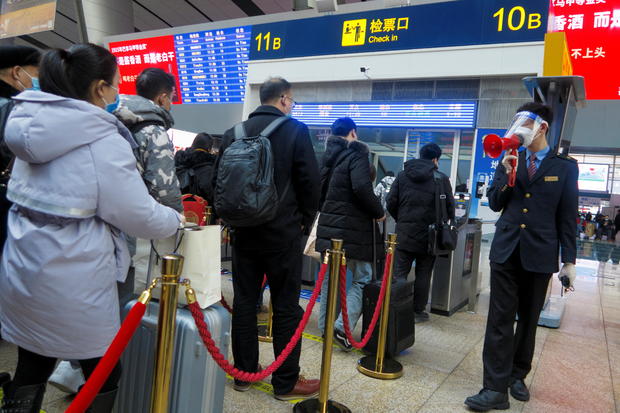 A station staff member speaks through a bullhorn to travellers waiting to board their train at Beijing South Railway station ahead of Lunar New Year celebrations following an outbreak of the coronavirus disease (COVID-19) in Beijing 