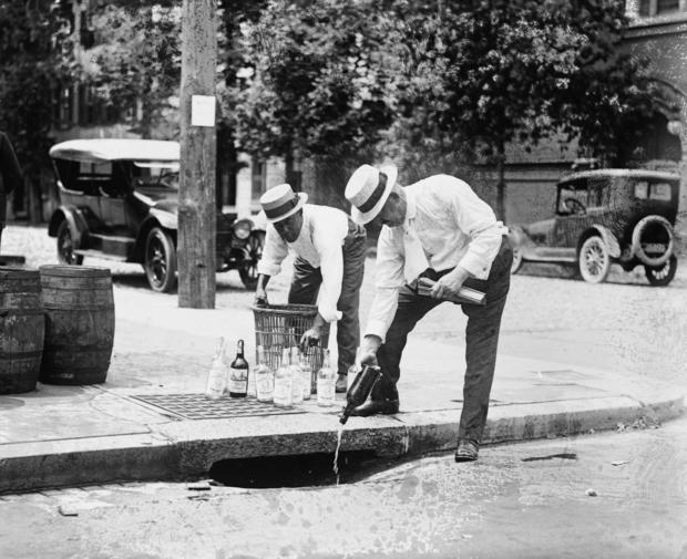 Agents Pouring liquor down a sewer on the Street 