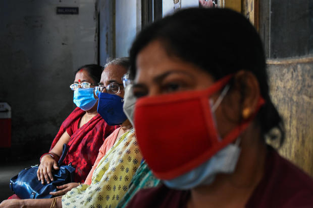 Women are wearing protective masks and waiting outside a 