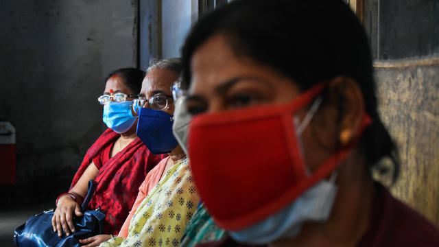 Women are wearing protective masks and waiting outside a 