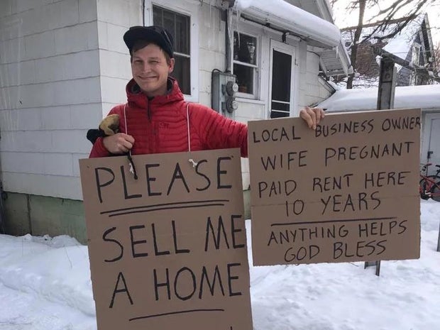 Sean Hawksford posing with a street sign after being outbid on 20 homes in Bozeman, Montana 