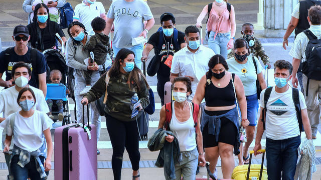 Travelers wearing protective face masks arrive at Orlando 