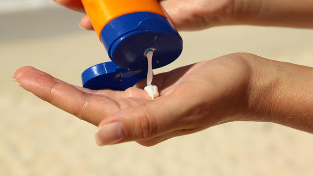 woman holding sunscreen bottle at beach 