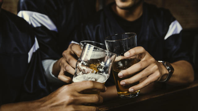 Male football fans toasting beer glasses in bar 