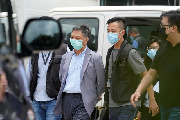 Police officers from the national security department escort Chief Operating Officer Chow Tat-kuen from the offices of Apple Daily and Next Media in Hong Kong 