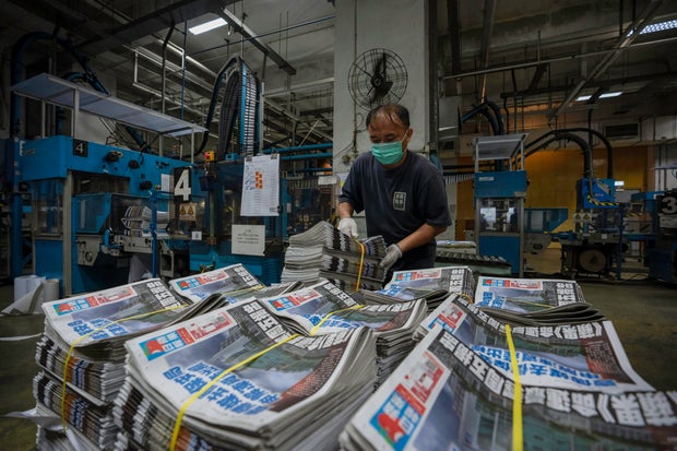 An employee stacks freshly printed papers onto a pallet in