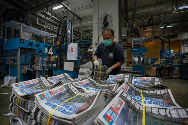 An employee stacks freshly printed papers onto a pallet in 