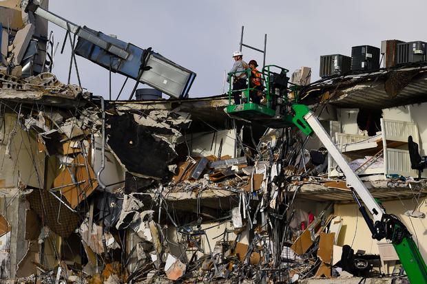 Rescue workers on a crane inspect the wreckage of the collapsed condo building in Surfside, Florida 