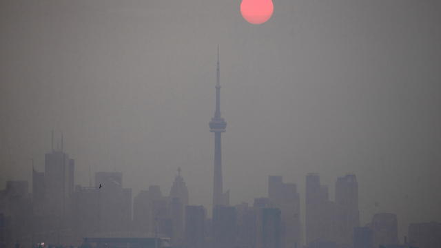 The sun rises through a cover of wildfire smoke above the CN Tower and downtown skyline in Toronto 