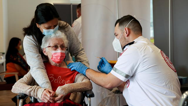 FILE PHOTO: An elderly woman receives a booster shot of her vaccination against the coronavirus disease (COVID-19) at an assisted living facility, in Netanya 