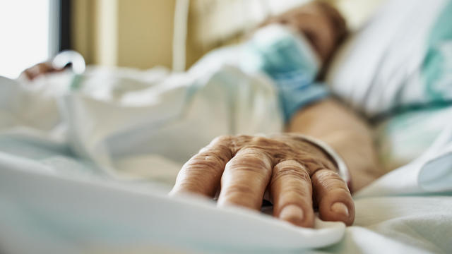 Senior woman wearing face mask lying on hospital bed 