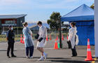 Staff members wearing face masks stand at a Covid testing 