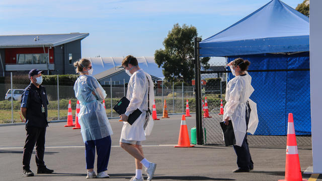 Staff members wearing face masks stand at a Covid testing 