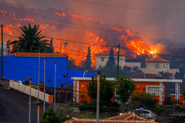 Lava flows behind houses following the eruption of a volcano in Spain 