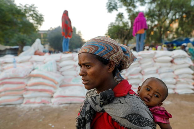 Woman carries an infant as she queues in line for food in Tigray region of Ethiopia 