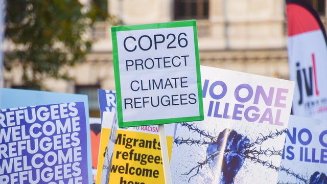 A placard reading "COP26 protect climate refugees" 