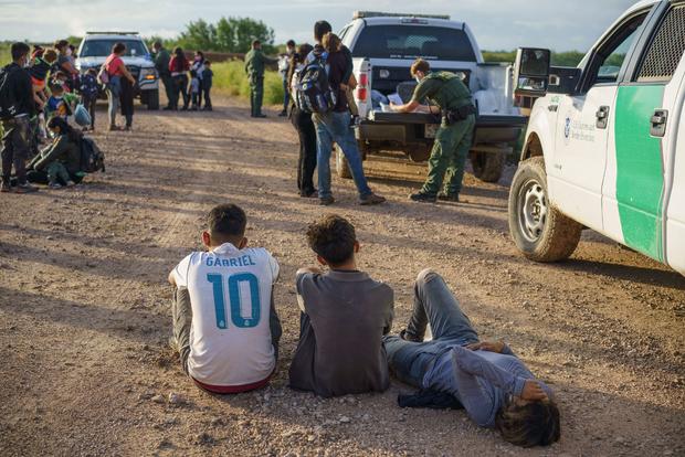 Immigrants at the U.S. - Mexico border with Border Patrol agents 