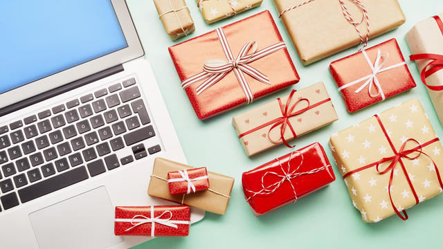 High angle view of a laptop computer and gifts on turquoise background, online shopping 