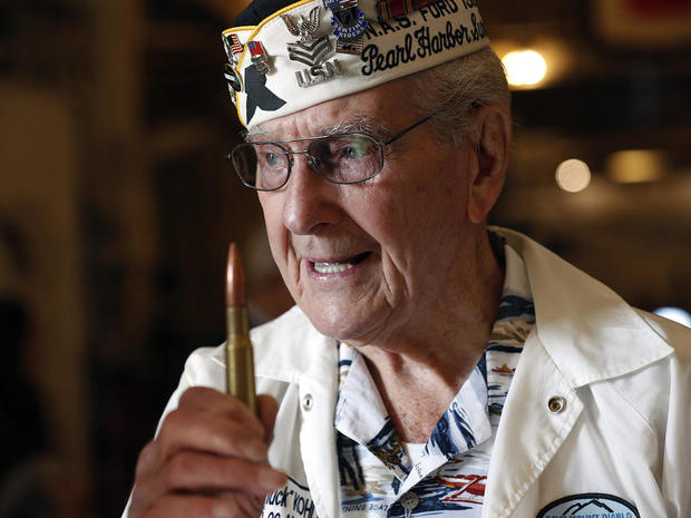 Pearl Harbor survivor E.J. "Chuck" Kohler uses a 50 caliber bullet to demonstrate how he grabbed a machine gun and starting shooting at enemy aircraft during the attack, at a ceremony on the 76th anniversary of the bombing of Pearl Harbor aboard the USS H 