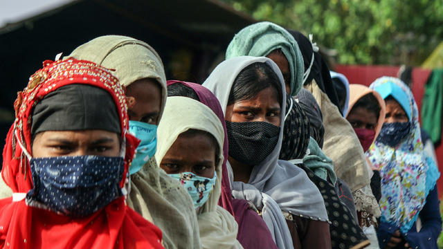 Rohingya women wearing masks are seen in a queue to undergo 