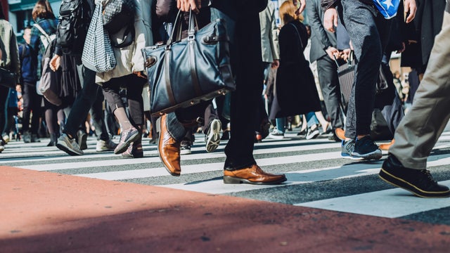 Low section view of a crowd of busy commuters crossing street in Shibuya crossroad, Tokyo 
