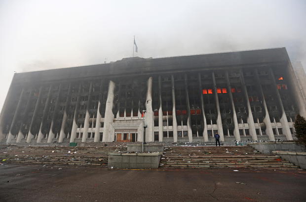 A man stands in front of the mayor's office building which was torched during protests in Almaty 