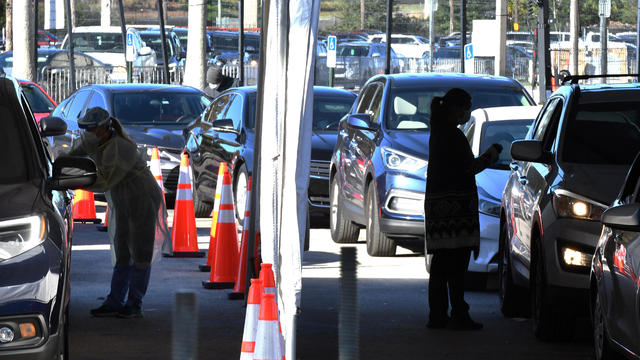 Healthcare workers collect nasal swab samples at a drive- 