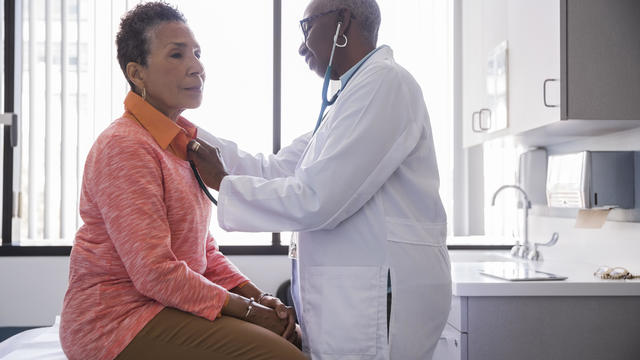 Smiling female doctor examining senior patient in hospital 