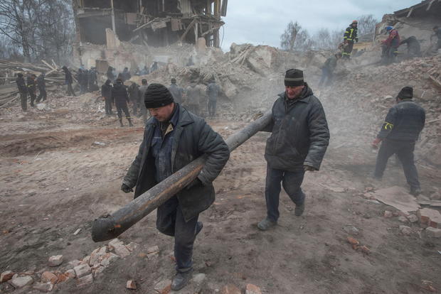 People remove debris at the site of a military base building that, according to the Ukrainian ground forces, was destroyed by an air strike, in the Sumy region 