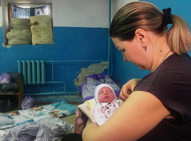 A woman holds her newborn baby as they take shelter in the basement of a perinatal centre in Kharkiv 