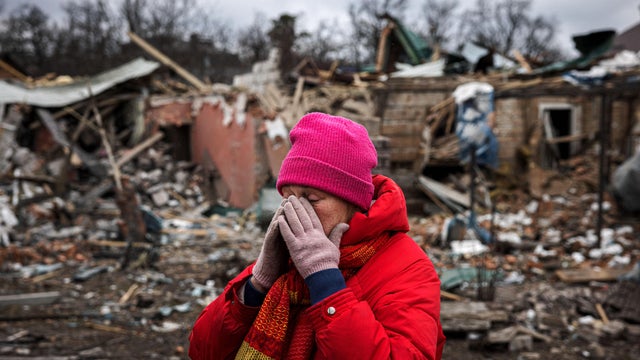 Irina Moprezova, 54, reacts in front of a house that was damaged in an aerial bombing in the city of Irpin, northwest of Kyiv, on March 13, 2022. 