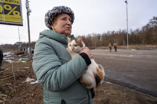 A woman carries her pet cat as she evacuates from the 