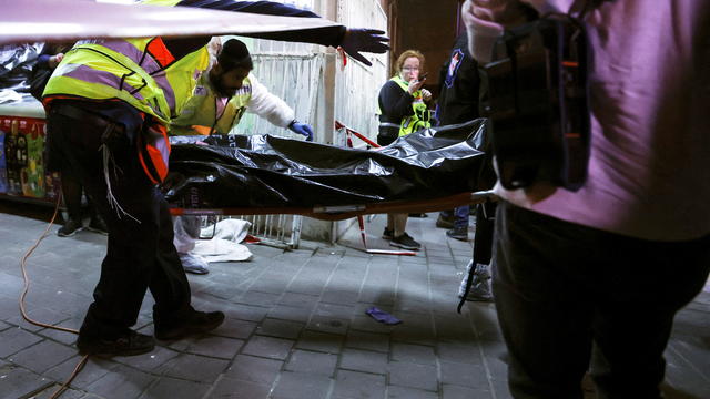 Israeli medical personnel and rescue workers evacuate a body from the scene of a fatal shooting attack on a street near Tel Aviv 