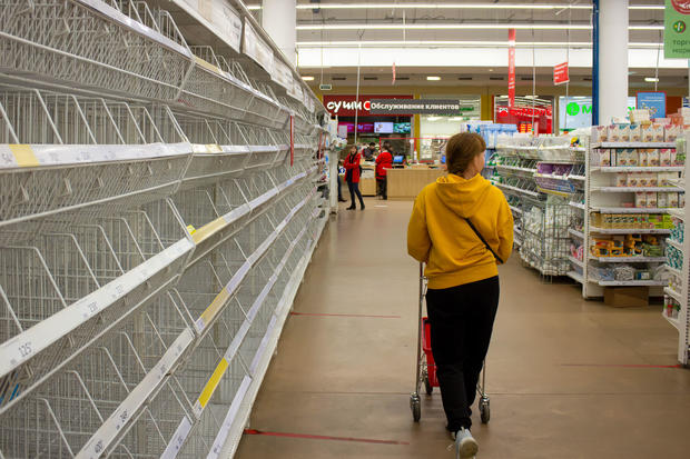 A woman walks by empty shelves in a supermarket in Moscow. 