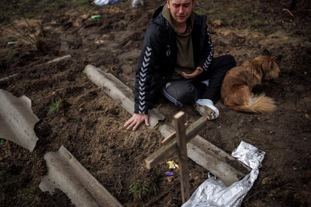 Serhii Lahovskyi mourns next to the grave of his friend Ihor Lytvynenko, in Bucha 