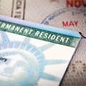 A Green Card lying on an open passport, close-up, full frame 