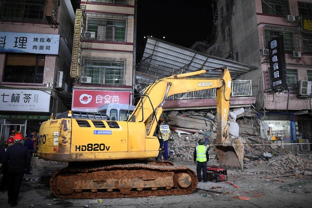 Rescuers work next to an excavator at a site where a building collapsed in Changsha, Hunan