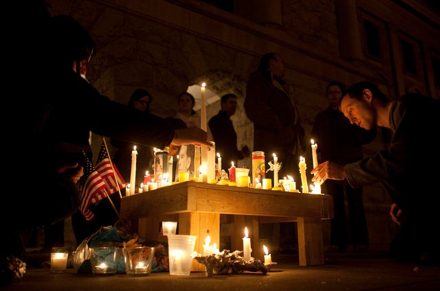 People pay their respects and light candles at a memorial for the victims of the shooting in Tucson 
