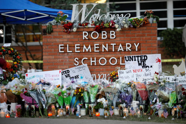 Flowers, candles and signs are left at a memorial for victims of the Robb Elementary School shooting, three days after a gunman killed nineteen children and two teachers, in Uvalde, Texas, May 27, 2022. 