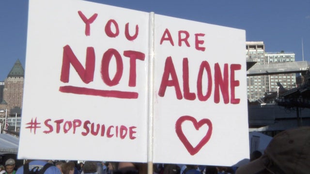 A sign reading "You are not alone #StopSuicide" at a suicide prevention walk