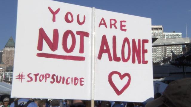 A sign reading "You are not alone #StopSuicide" at a suicide prevention walk 
