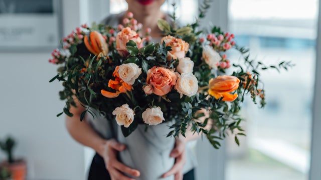 Shot of an unrecognisable woman covering her face with flowers in living room 