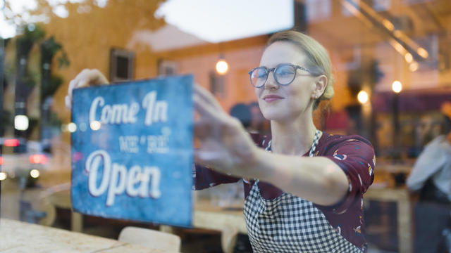 Business owner setting up open sign in cafe window 