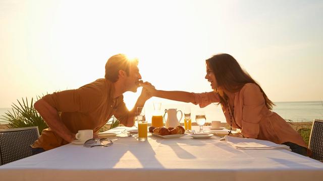 Hispanic woman feeding man at sunset dinner outdoors 