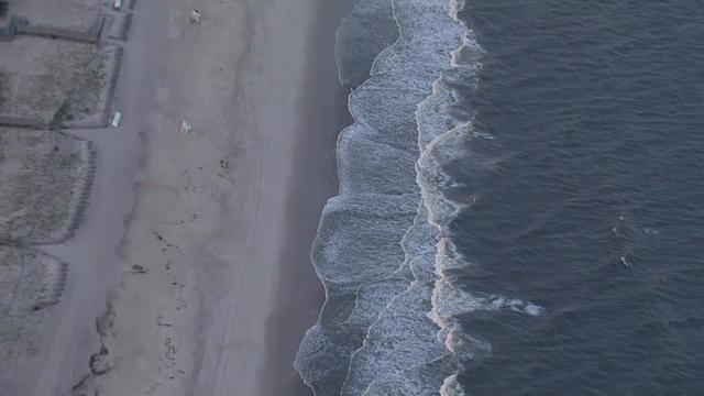 An aerial shot of an empty beach and the ocean. 