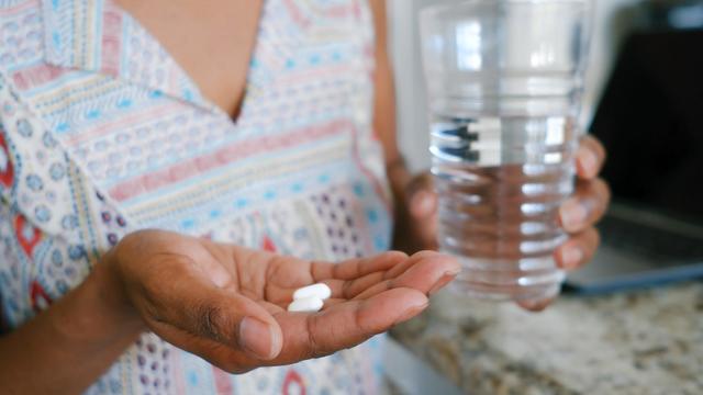 Woman Holds Pills in Palm of Hand 