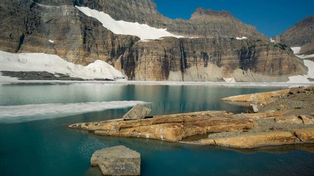 Glacial tarn and melting ice. Grinnell Glacier, northern Montana. Bedrock consists of the Proterozoic Helena Dolomite of the Belt Supergroup. the waterfall in the background drains the retreating Salamander Glacier. 
