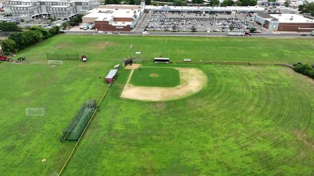 An aerial shot of a large green field with a baseball diamond, soccer nets and other sports equipment. 