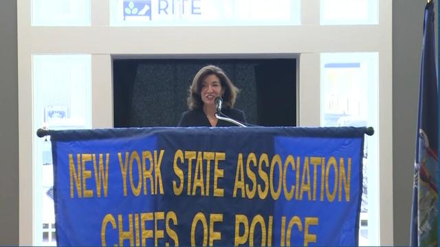 Gov. Kathy Hochul stands behind a podium with a banner reading "New York State Association Chiefs of Police." 