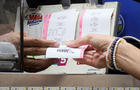 A woman buys a ticket for the Mega Millions lottery drawing at a newsstand in New York City, July 26, 2022. 